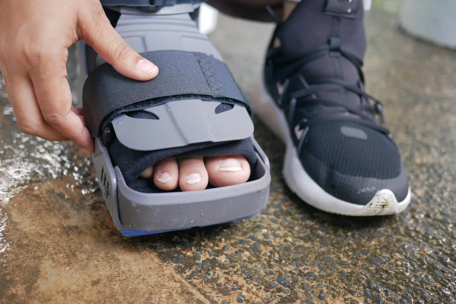 A person adjusting a supportive foot brace beside a walking shoe