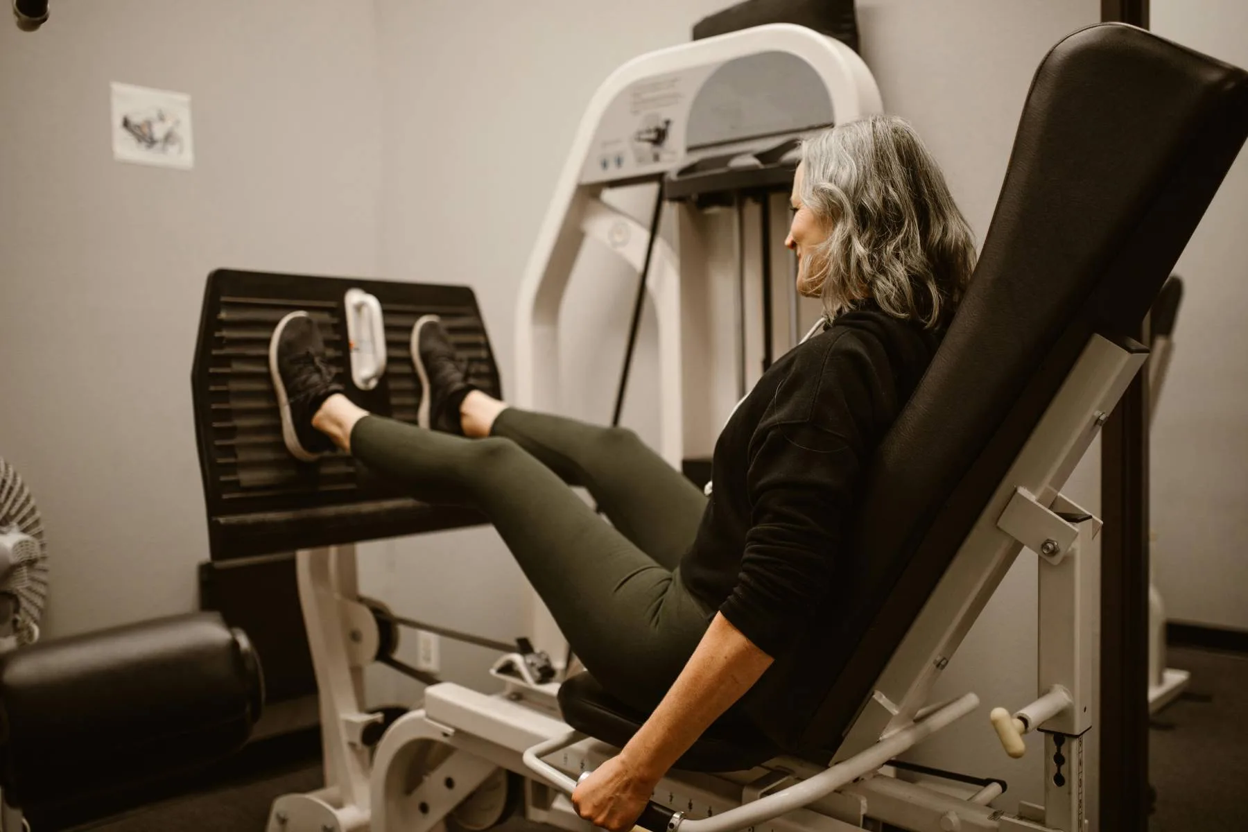 An adult using a seated leg-press machine