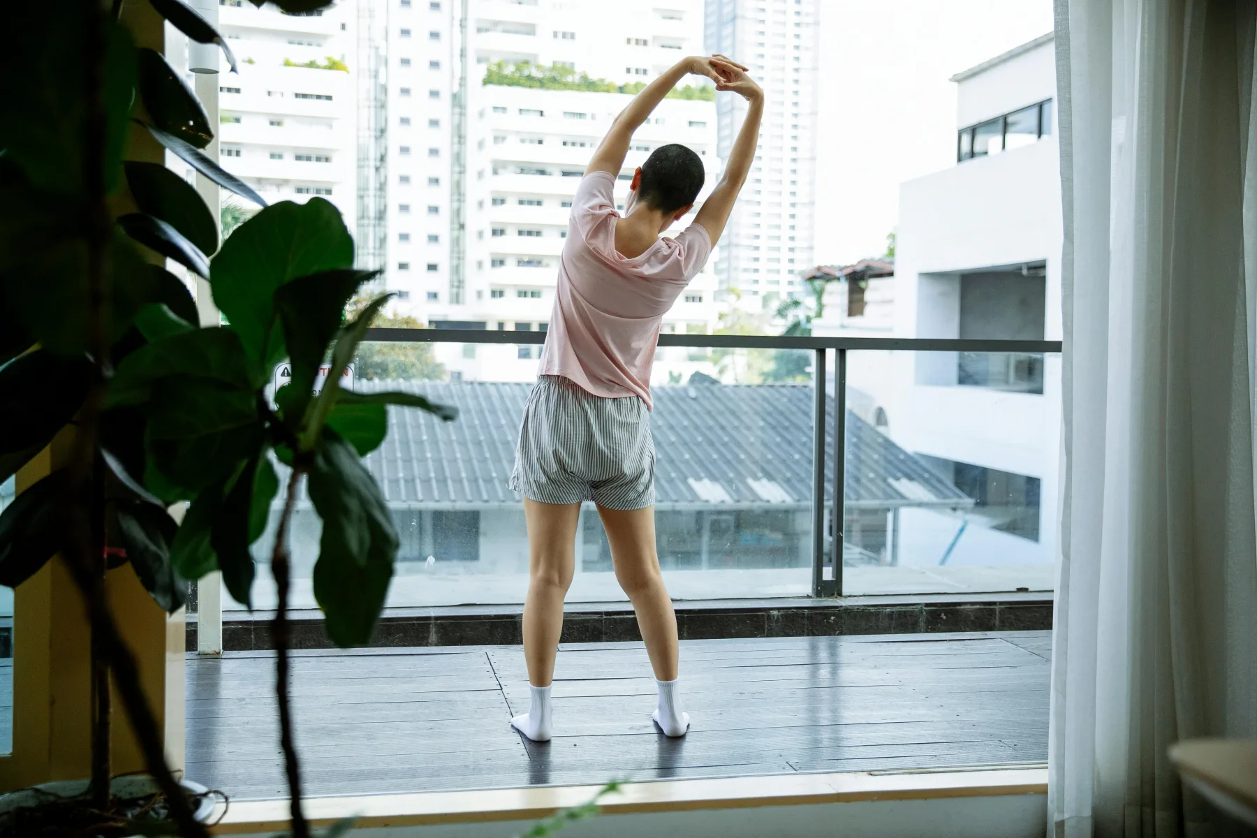 An adult beginning the day with a standing side stretch by an open window